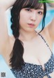 A woman in a black and white bikini posing by a pool.