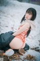 A woman in a bikini sitting in the snow.