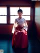 A woman in a red and white hanbok sitting in front of a window.