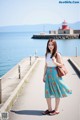 A woman standing on a sidewalk next to the water.