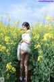 A woman standing in a field of yellow flowers.