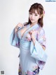 A woman in a blue kimono posing for a picture.