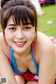 A woman in a blue and red bathing suit laying on the grass.