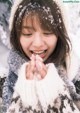 A young woman is smiling while playing in the snow.