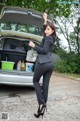 A woman in a business suit standing next to a car.