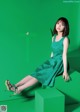 A woman in a green dress sitting on a green cube.