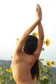 A naked woman standing in a field of sunflowers.