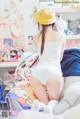 A woman in a yellow hat is sitting on a bed.