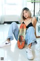 A woman sitting on the floor holding a skateboard.